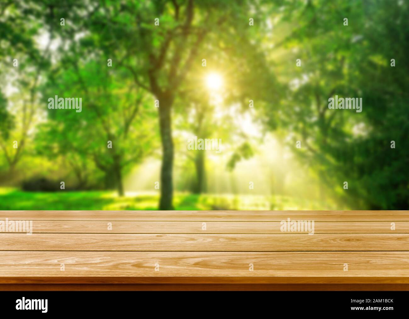 Brown wood table in green blur nature background of trees and grass in the park with empty copy space on the table for product display mockup. Fresh s Stock Photo