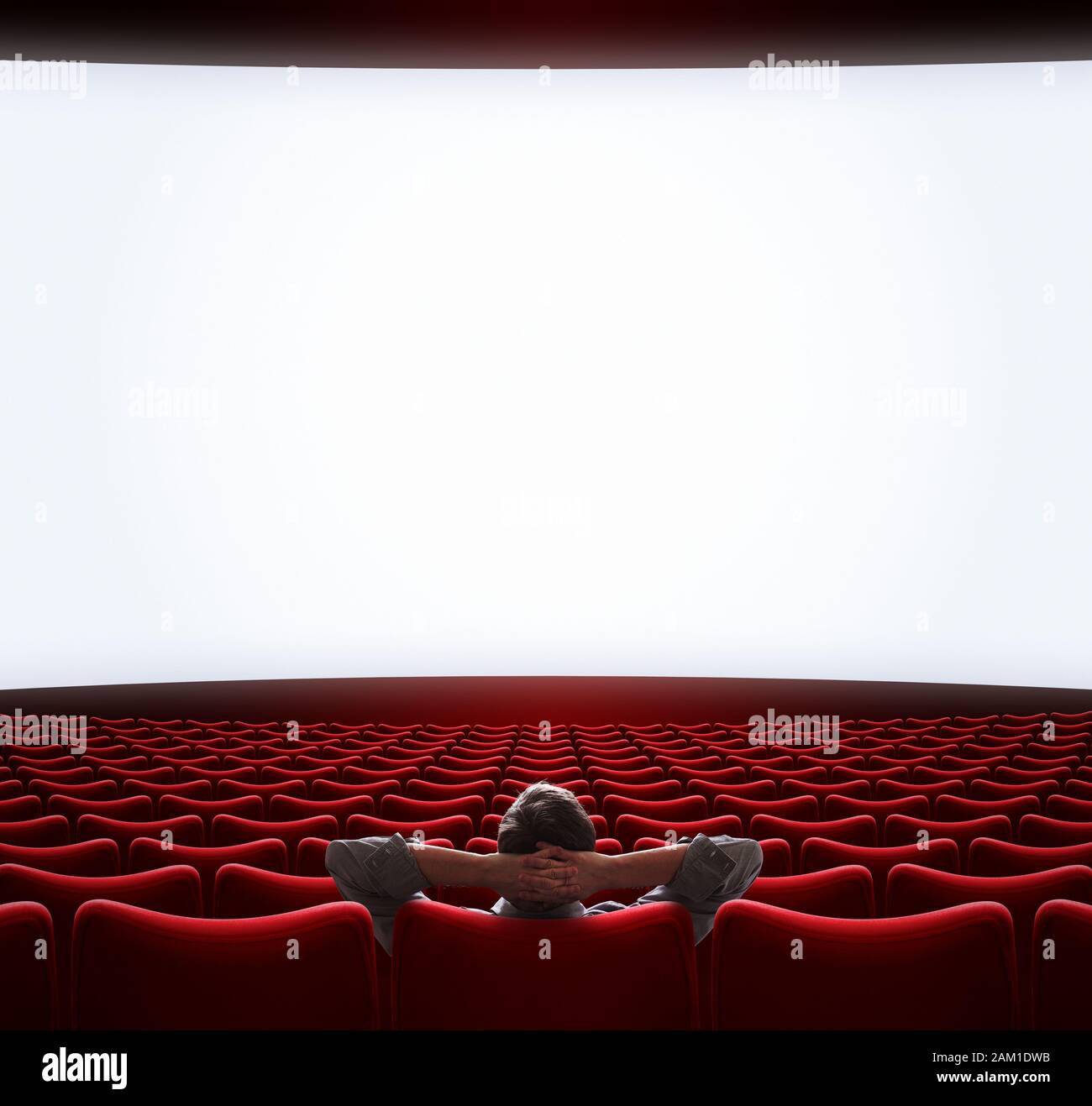 Blank movie screen with lonely man sitting in center Stock Photo