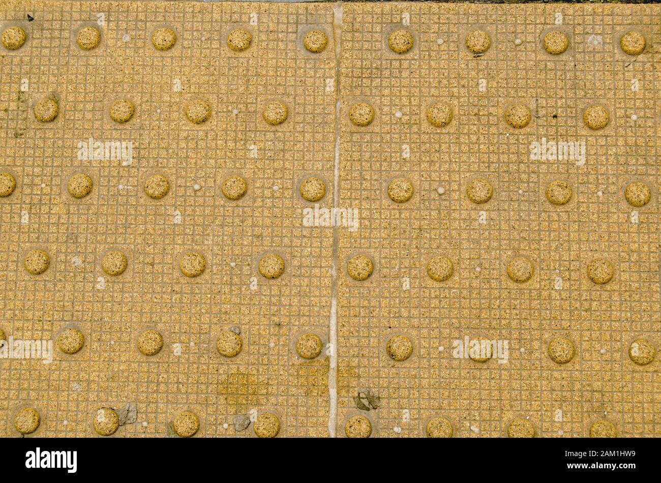 Detail of the internationally used tactile paving to help visually impaired people. These truncated domes are marking the edge of a railway platform. Stock Photo