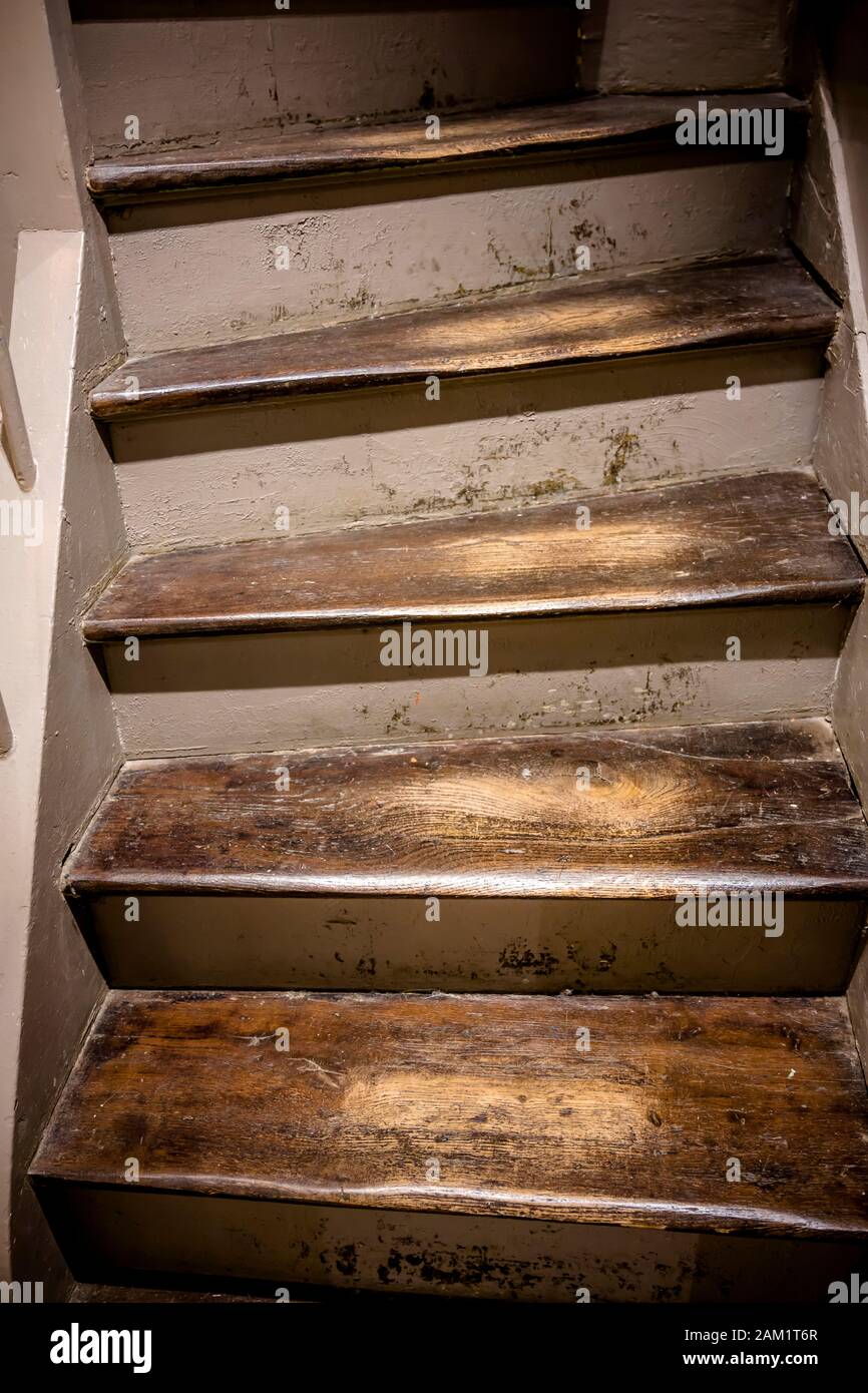 An old staircase with wooden steps with a varnish worn off from long