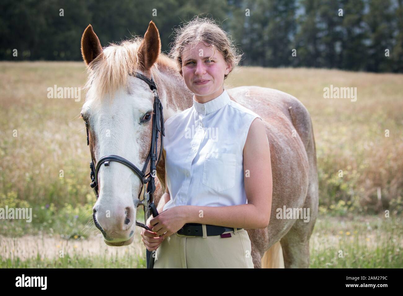 Girl standing next to her Sabino paint horse smiling both facing the camera. Stock Photo