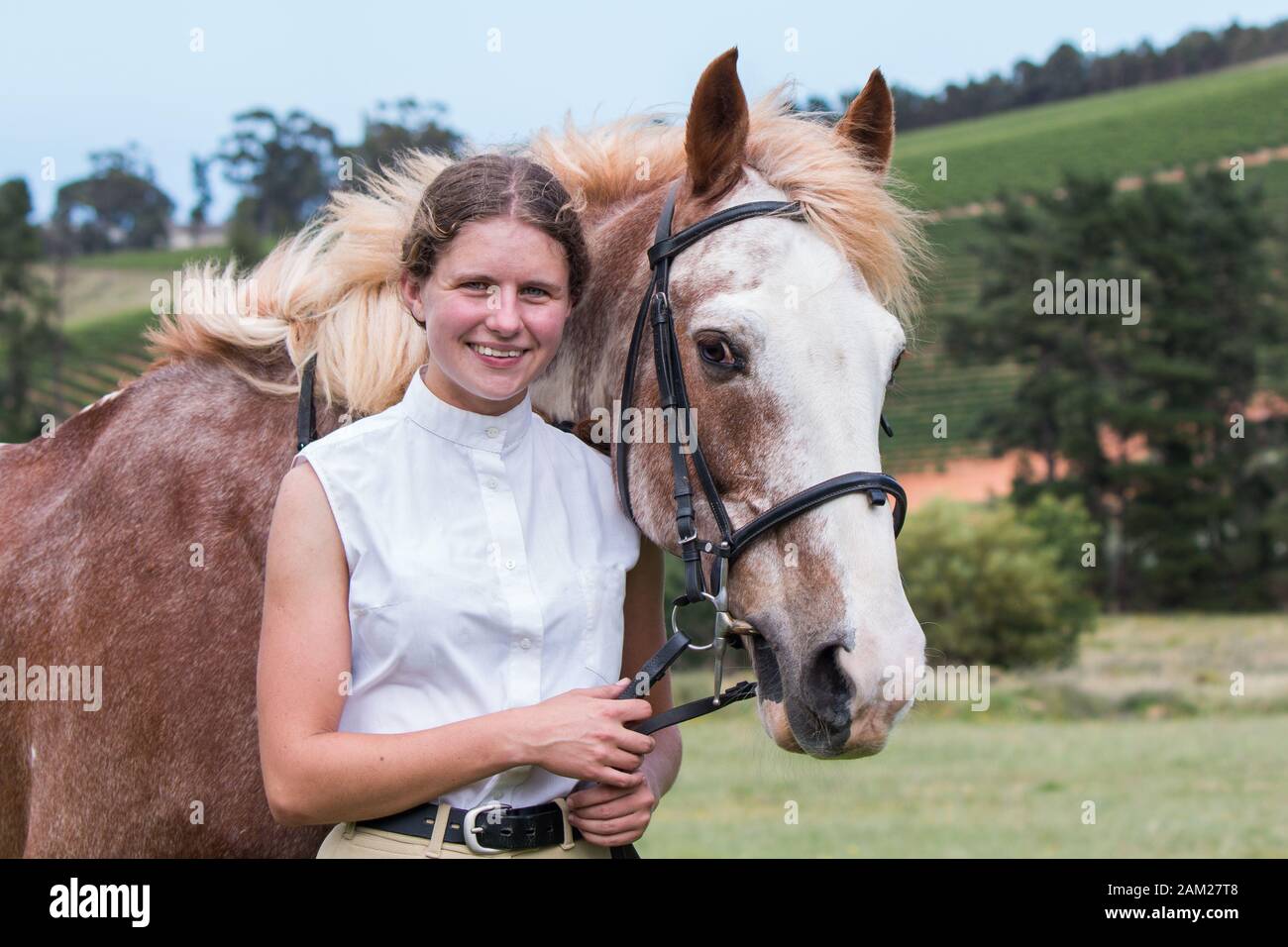Girl standing next to her Sabino paint horse smiling both facing the camera close up. Stock Photo