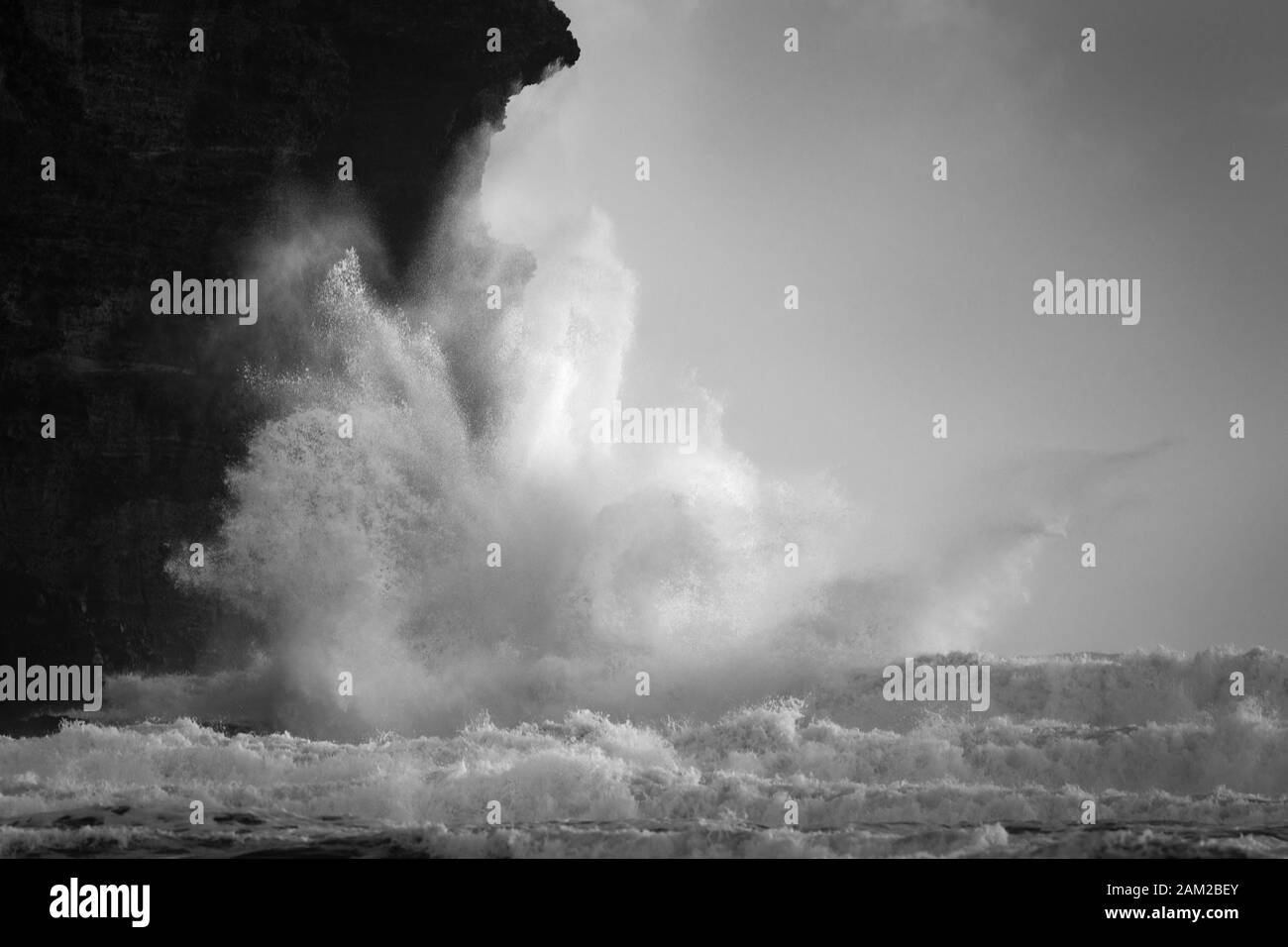 Black and white image of huge waves crashing against the rocks at Piha beach, Waitakere, New Zealand Stock Photo