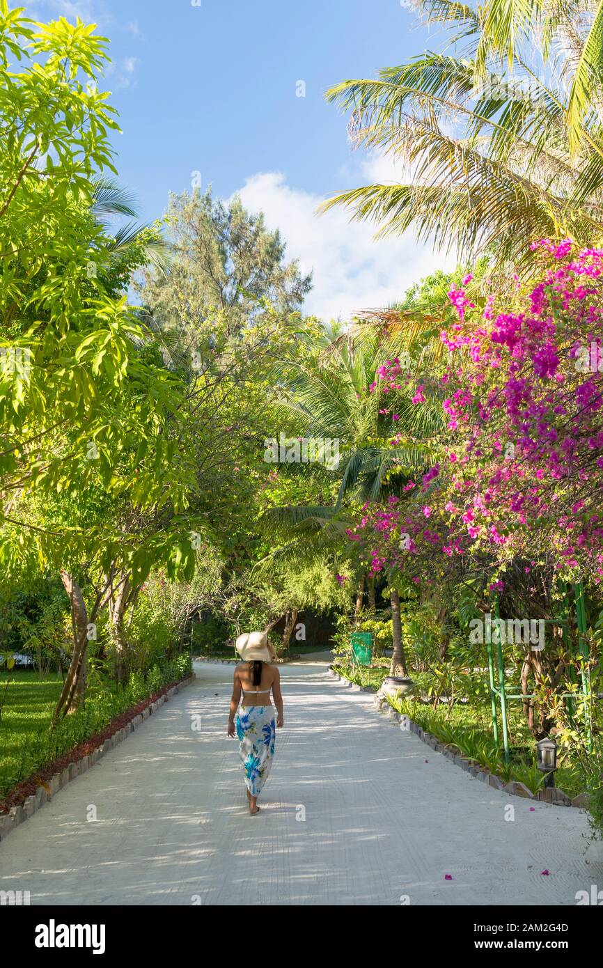 Woman walking in grounds of Olhuveli Beach and Spa Resort, South Male Atoll, Kaafu Atoll, Maldives Stock Photo