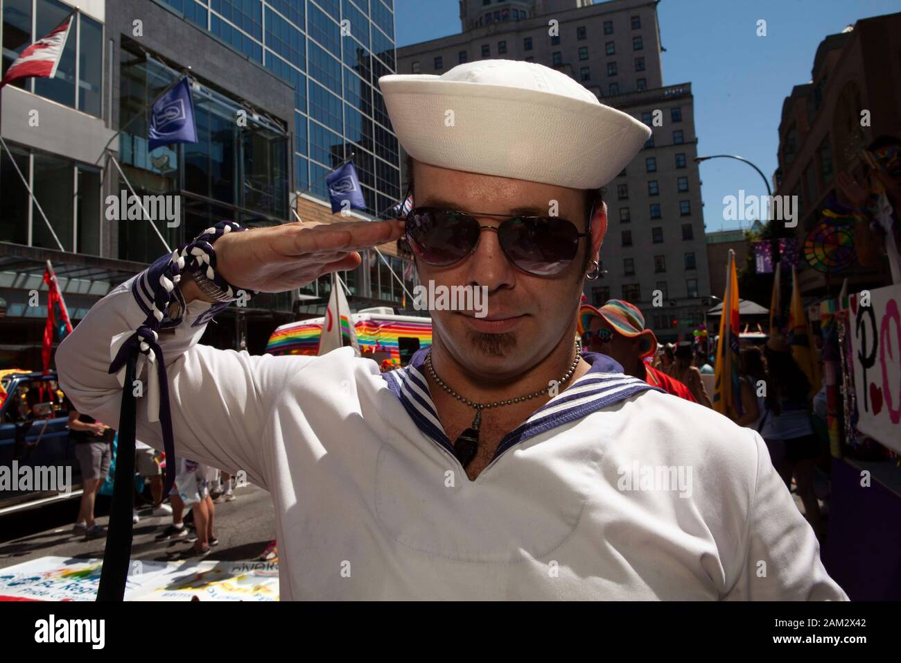 Pride parade participant in sailor costume saluting in street, crowd in background, Vancouver Pride Festival 2014, Vancouver, Canada Stock Photo