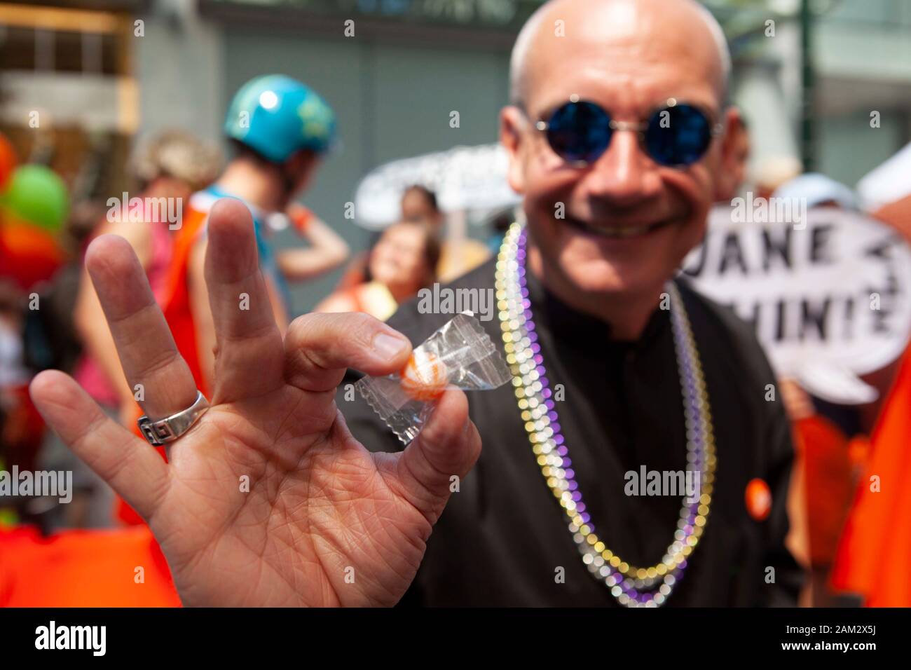 Pride parade participant offering sweet, crowd in background, Vancouver Pride Festival 2014, Vancouver, Canada Stock Photo
