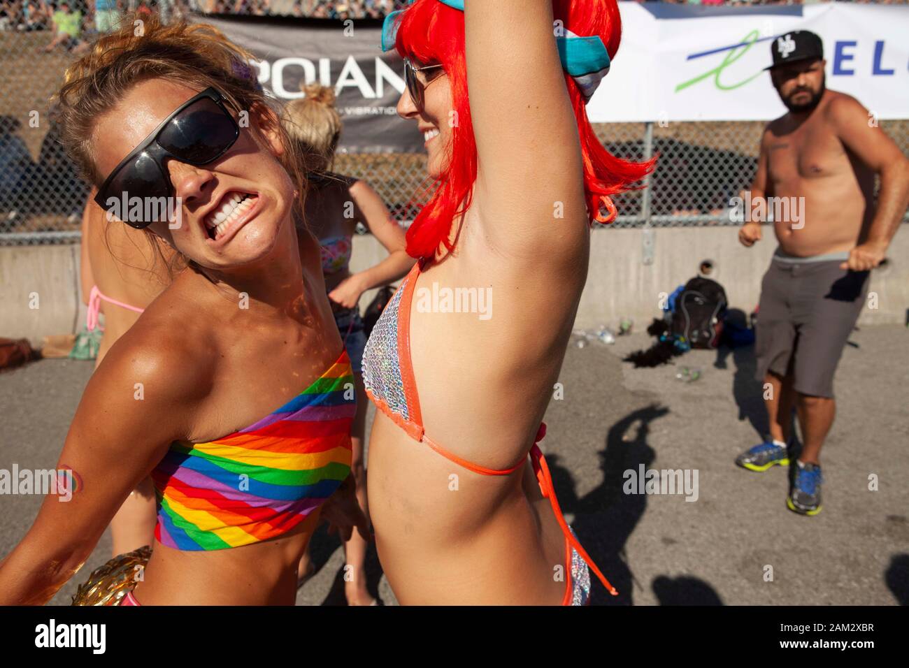 Friends dancing and chest bumping  in sun at festival, Vancouver Pride Festival 2014, Vancouver, Canada Stock Photo