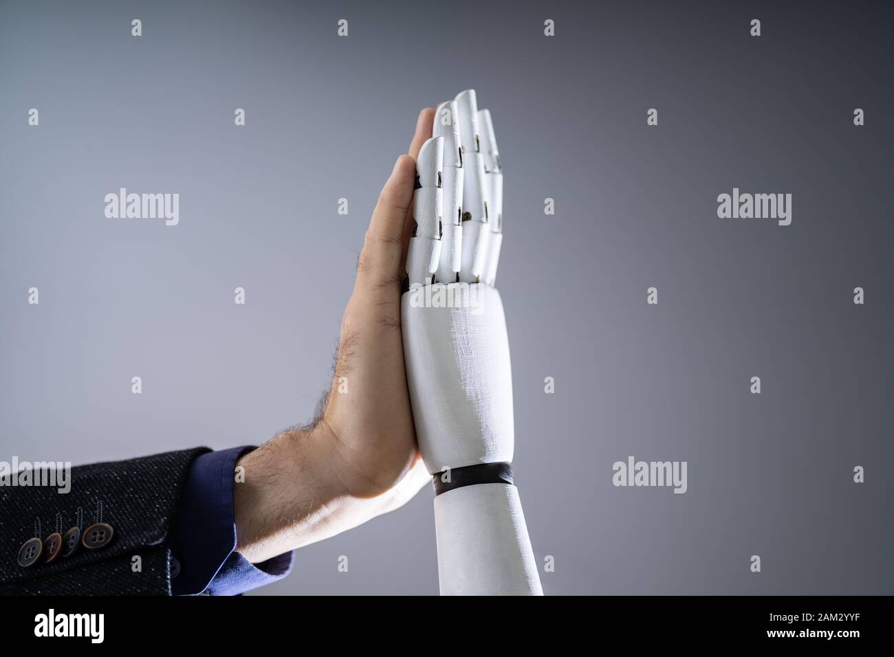 Close-up Of Robot And Man Giving High Five Against Digital Background Stock Photo