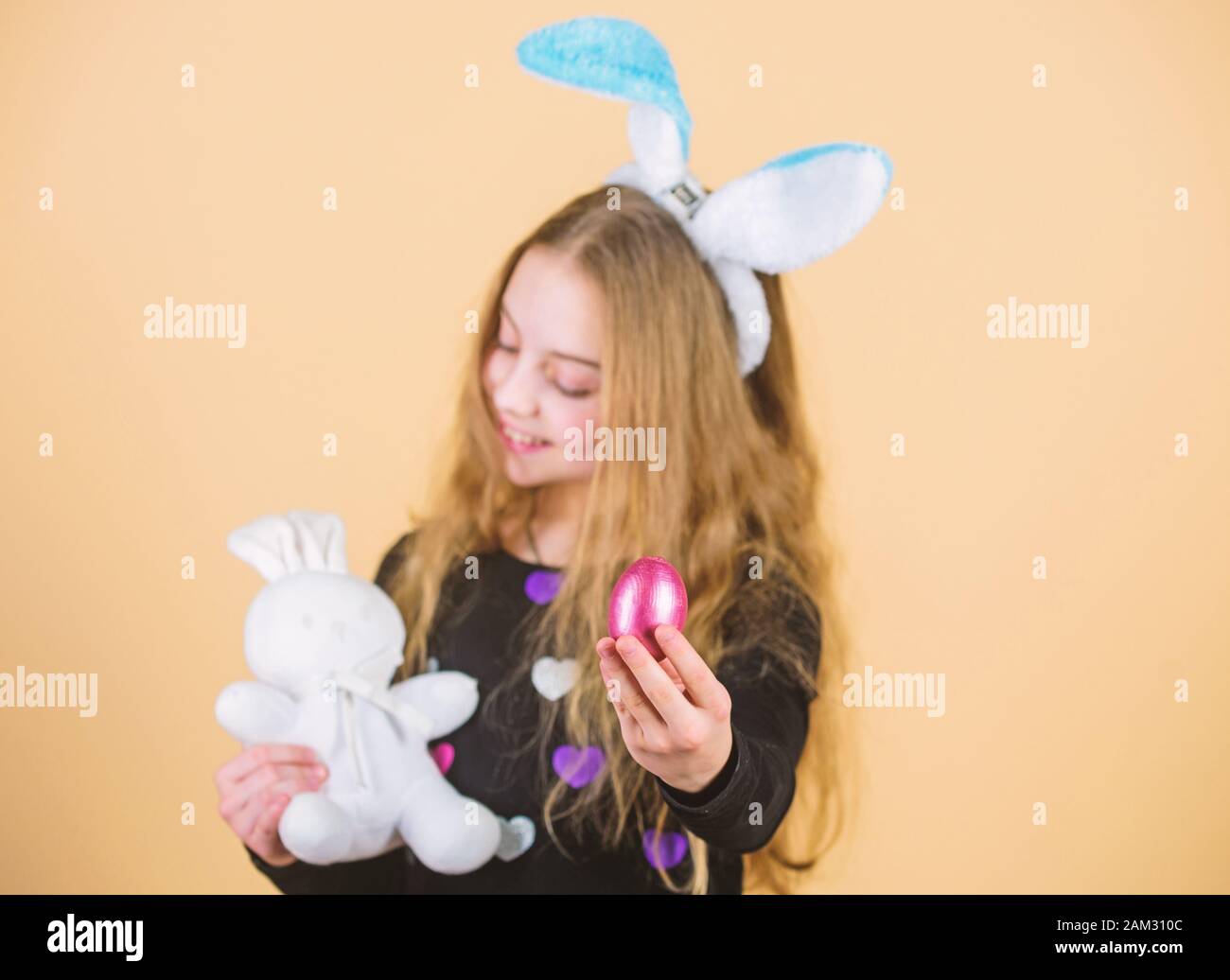 Egg feast. Little girl holding Easter egg and bunny toy. Cute child