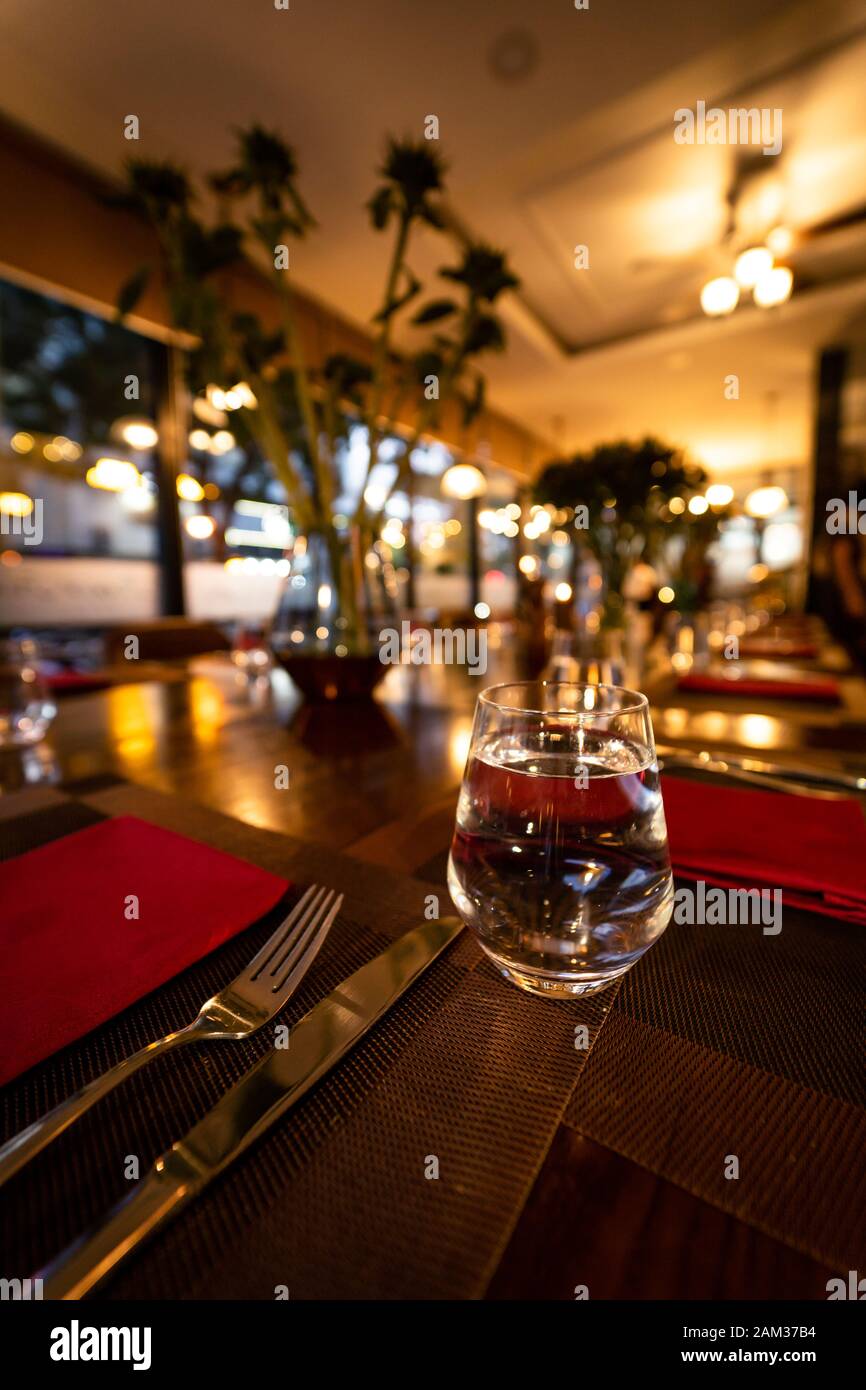 Glass of water on the table with knife and tablecloth inside a restaurant - Restaurant interior with luxury decoration Stock Photo