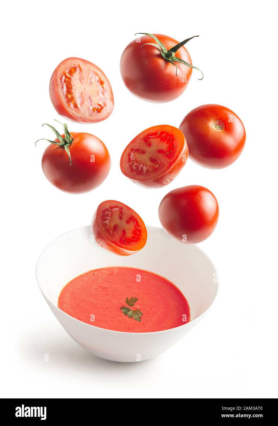 Fresh tomatoes flying, homemade tomato cream bowl, crushed tomato, white isolated background. flying vegetables concept Stock Photo