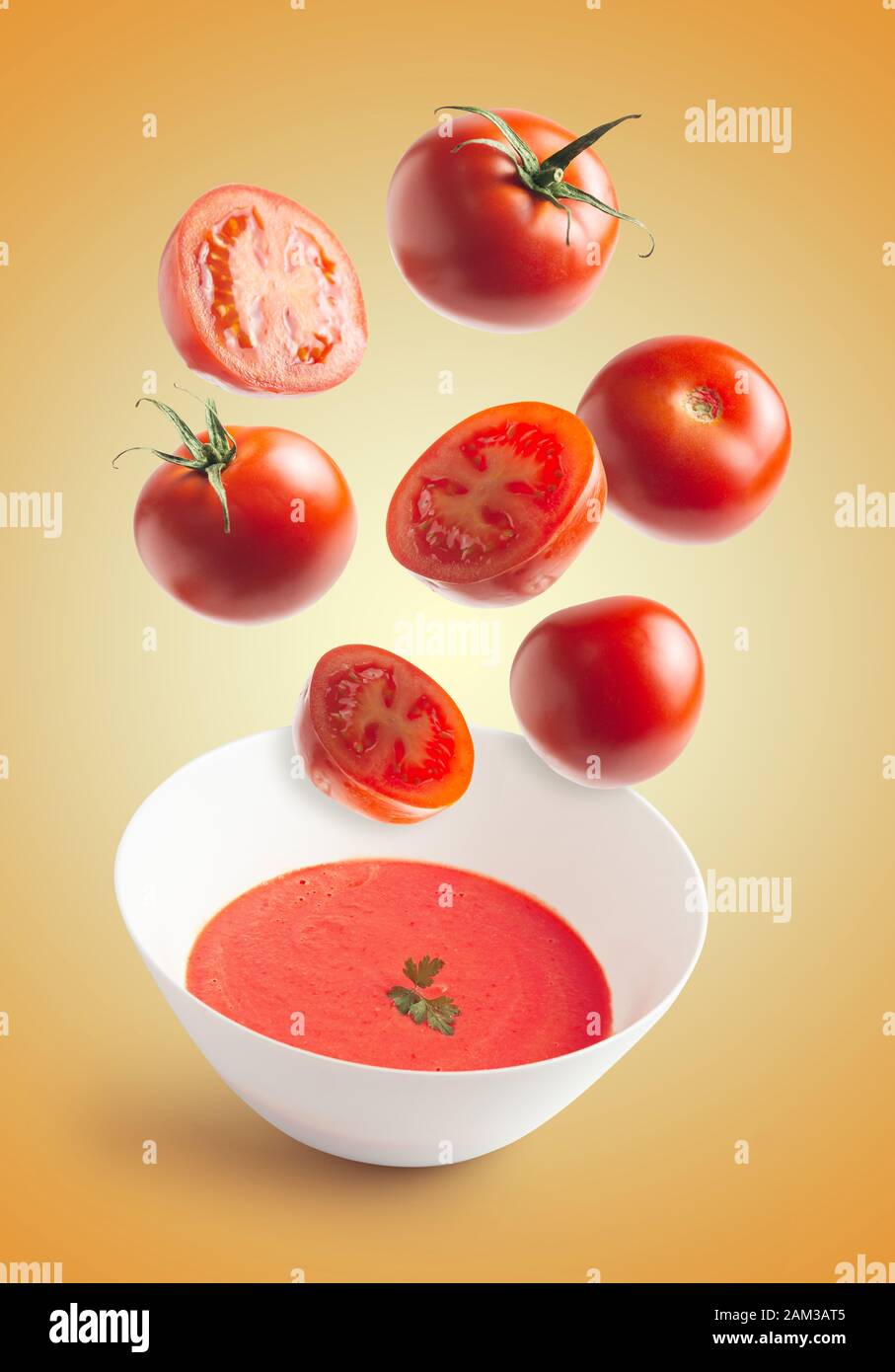 Fresh tomatoes flying, homemade tomato cream bowl, crushed tomato, yellow isolated background. flying vegetables concept Stock Photo