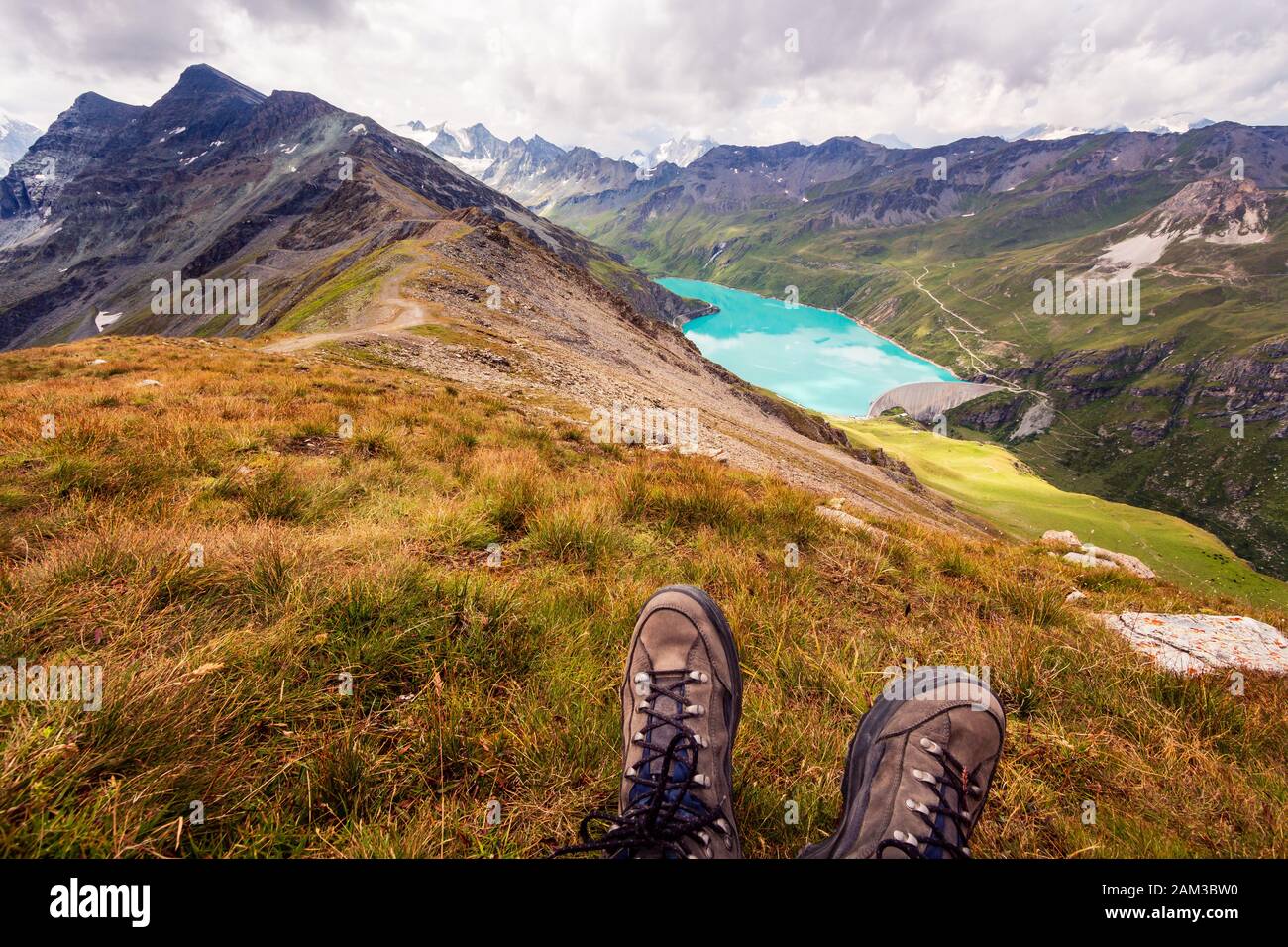 Enjoy breathtaking view from the top of a mountain on a mountain lake. First person perspective of hiking shoes. Corne de Sorebois, Grimentz, Valais, Stock Photo