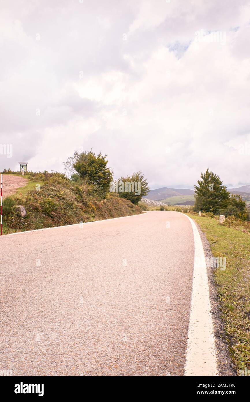 Winding mountain road between green fields and under autumn clouds. Road trip to the most beautiful. travel concept Stock Photo