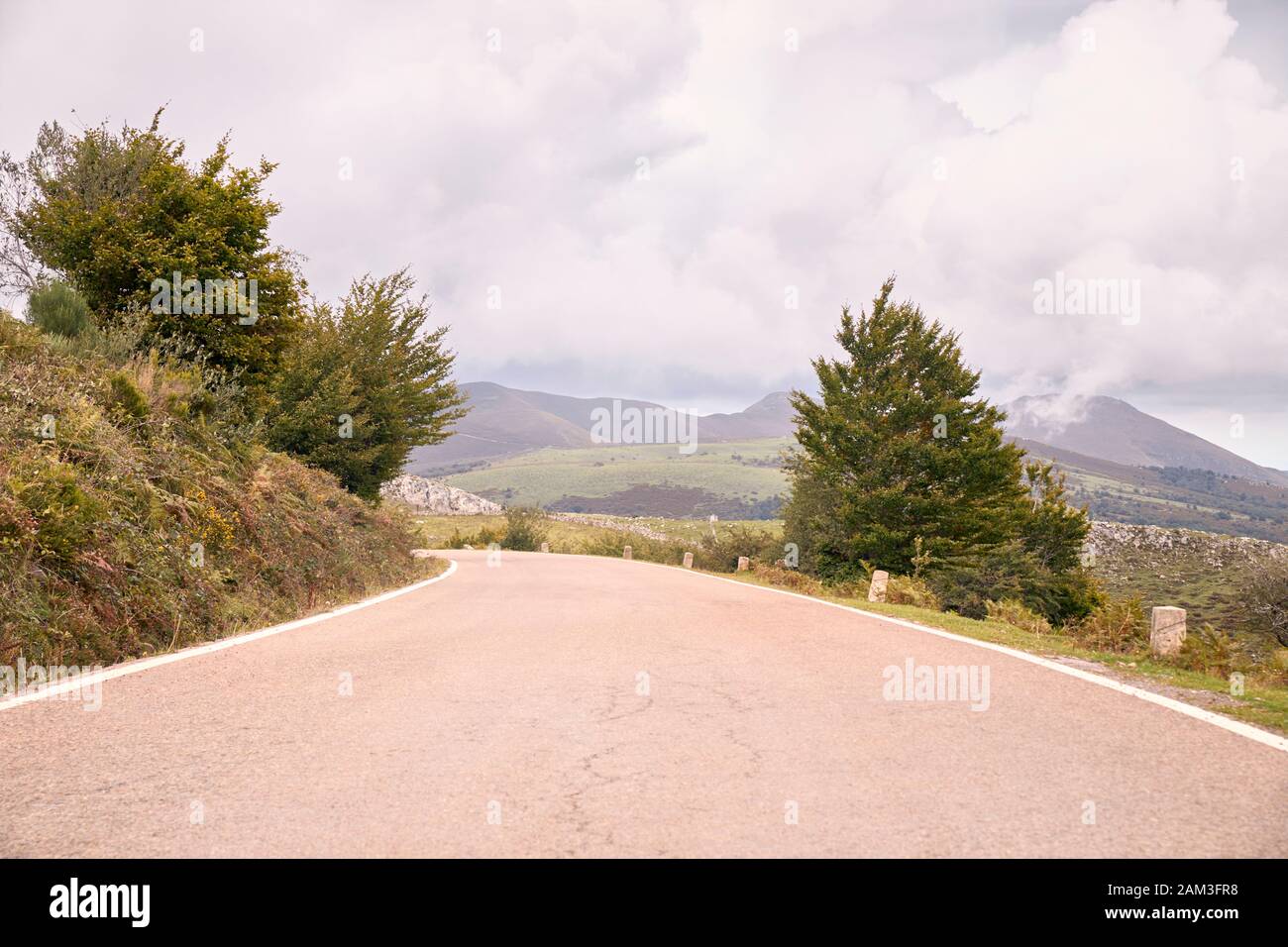 Winding mountain road between green fields and under autumn clouds. Road trip to the most beautiful. travel concept Stock Photo