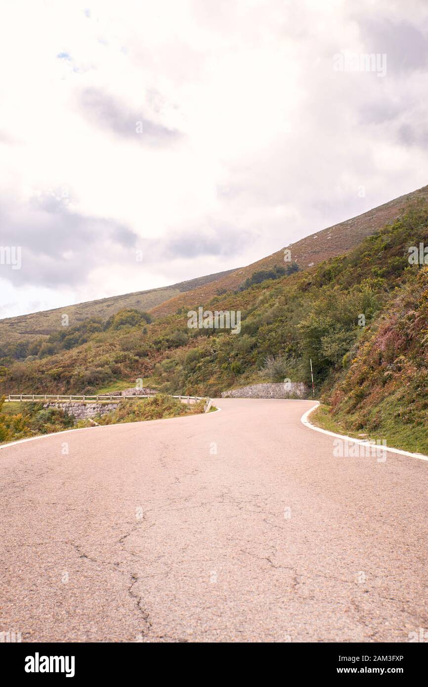 Winding mountain road between green fields and under autumn clouds. Road trip to the most beautiful. travel concept Stock Photo