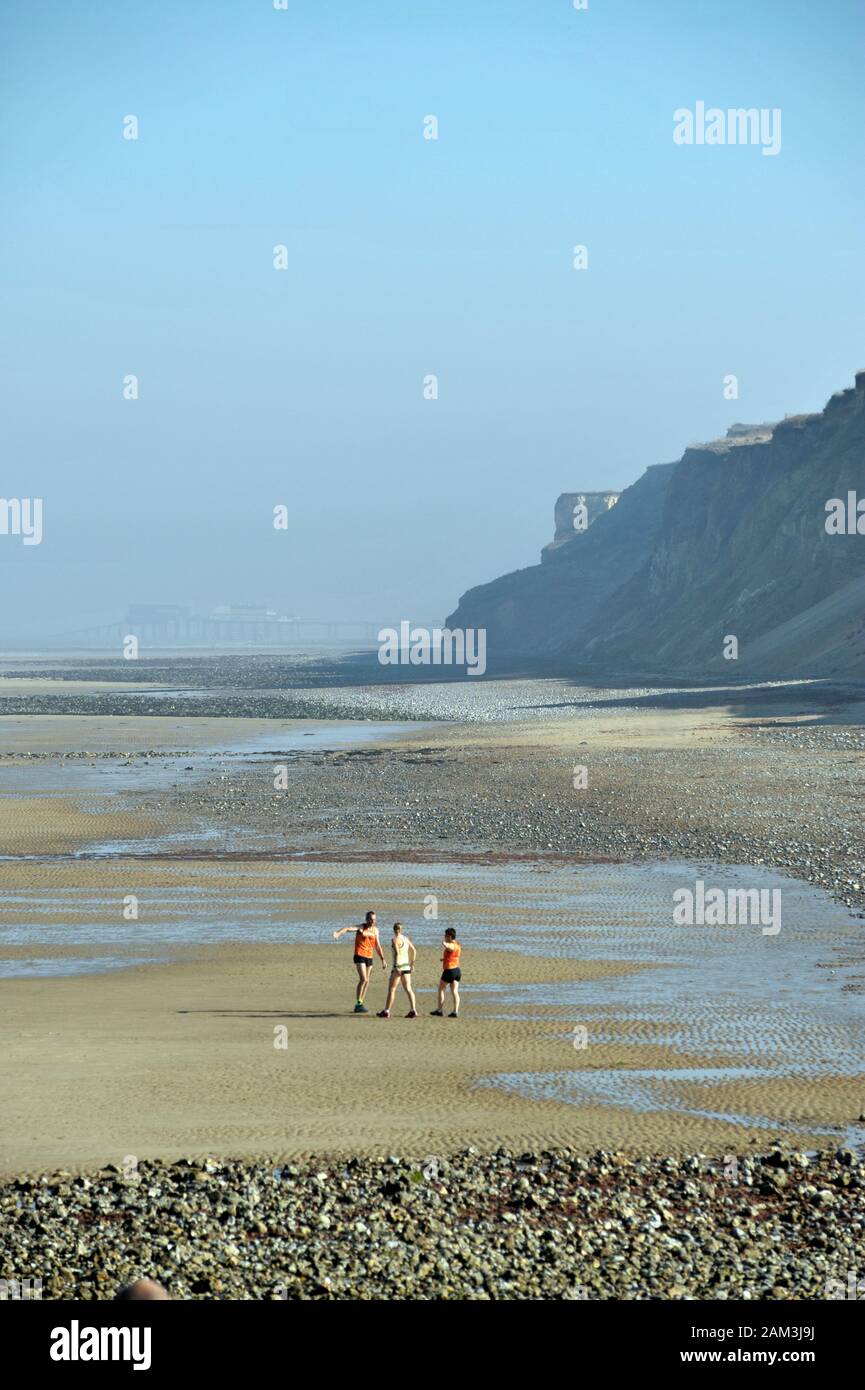 three people on beach at west runton north norfolk UK Stock Photo