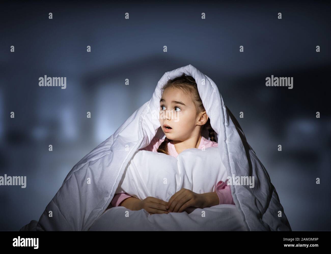 Scared girl with pillow hiding under blanket Stock Photo Alamy