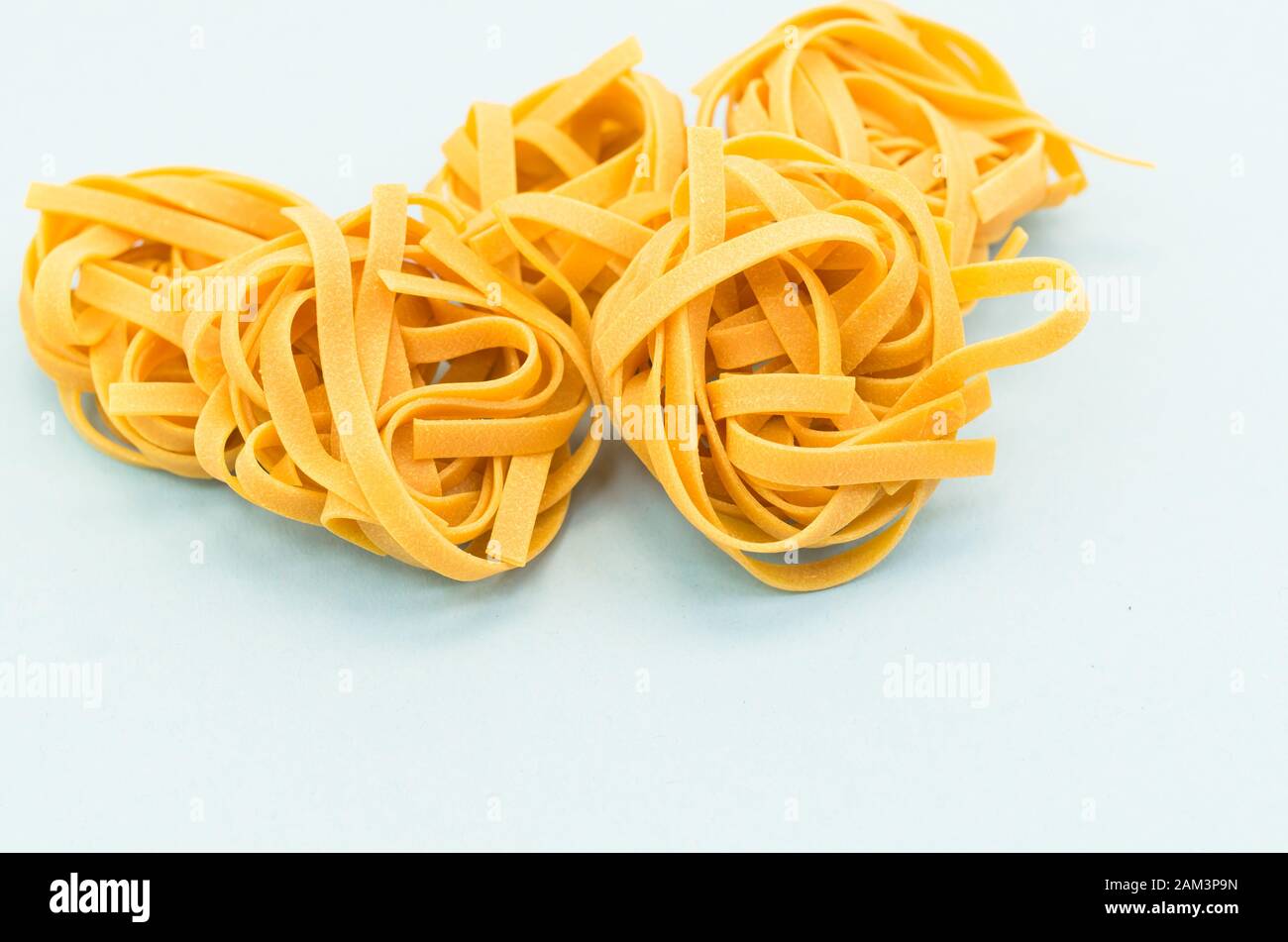 italian tagliatelle nest on a light blue background - natural food ...