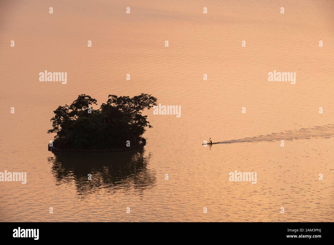 A lone canoeist paddles towards an island at sunset in the Seven Star Crags national park (Qixing Yan), near zhaoqing, People's Republic of China Stock Photo