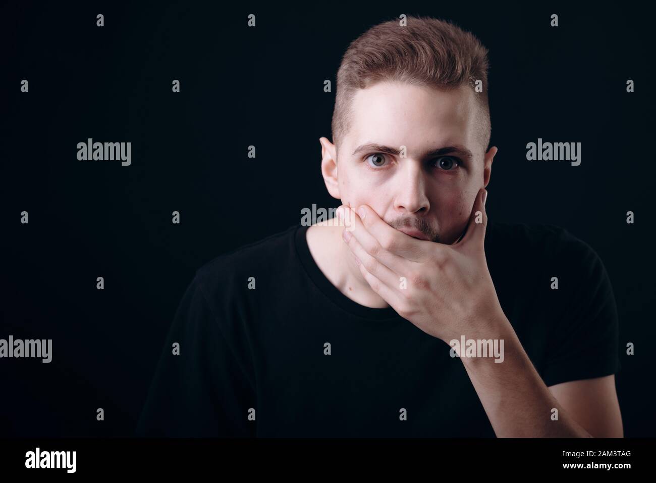 Astonished Young Man Covering His Mouth With Hand Stock Photo