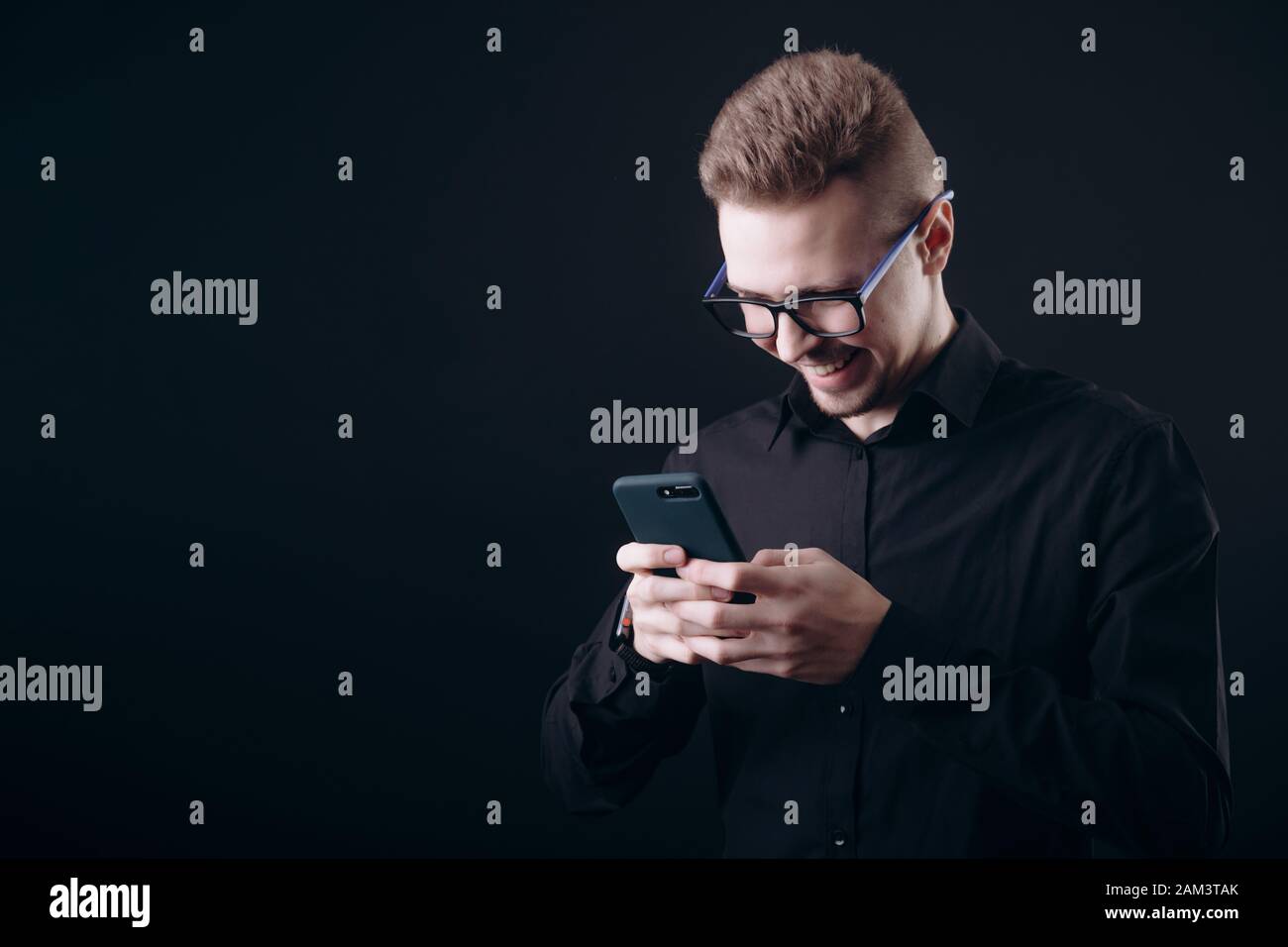 Smiling Bearded Young Man in Glasses Using Smartphone Stock Photo