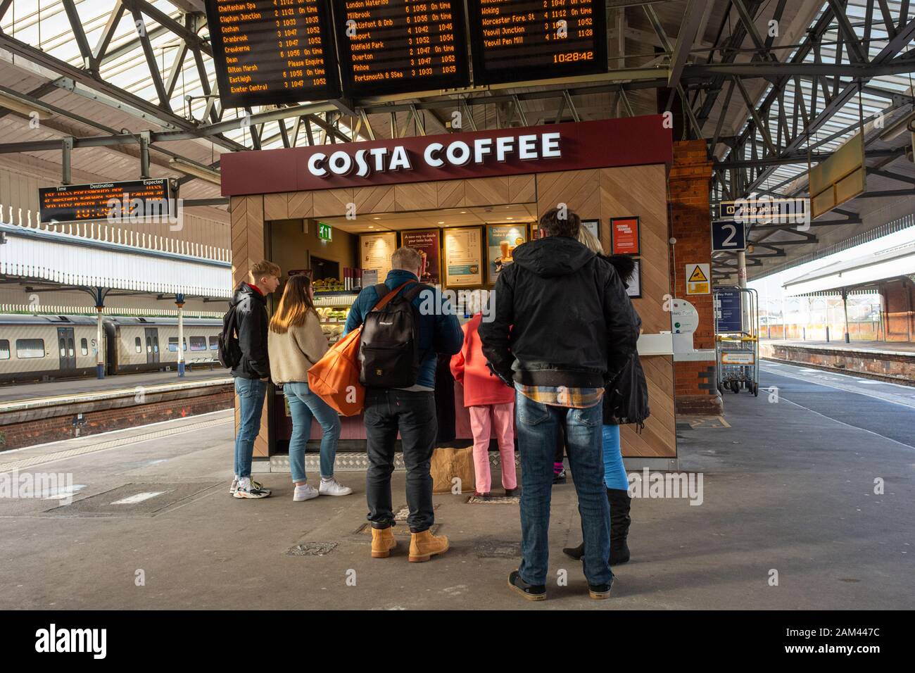 Passengers queuing at a kiosk selling Costa Coffee on a railway station ...