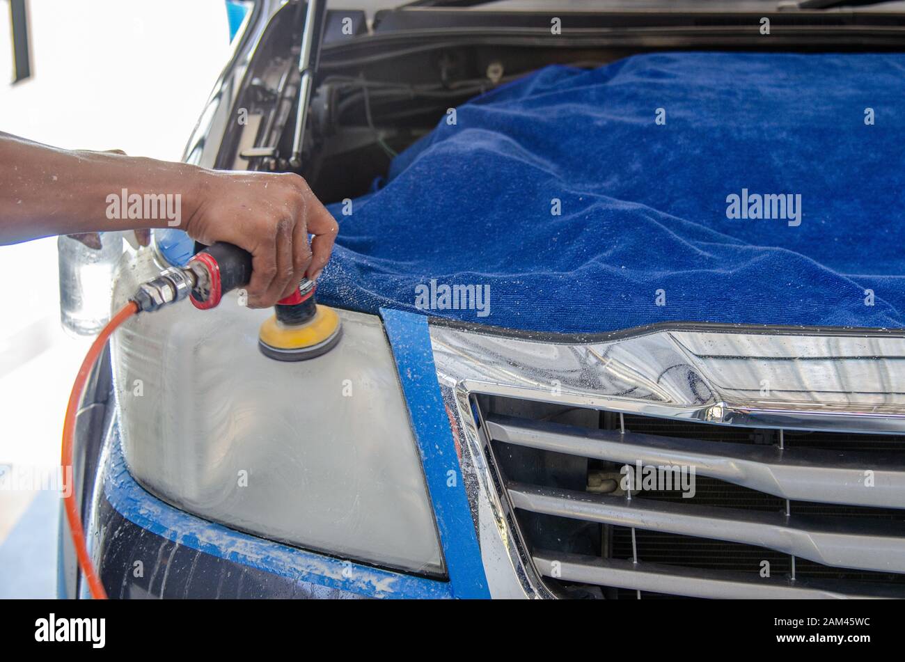 mechanic's hand is polishing the car's headlight Stock Photo Alamy