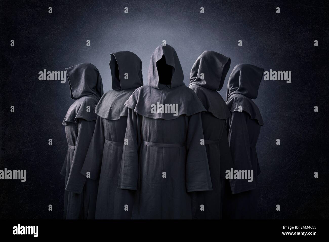 Group of five scary figures in hooded cloaks in the dark Stock Photo