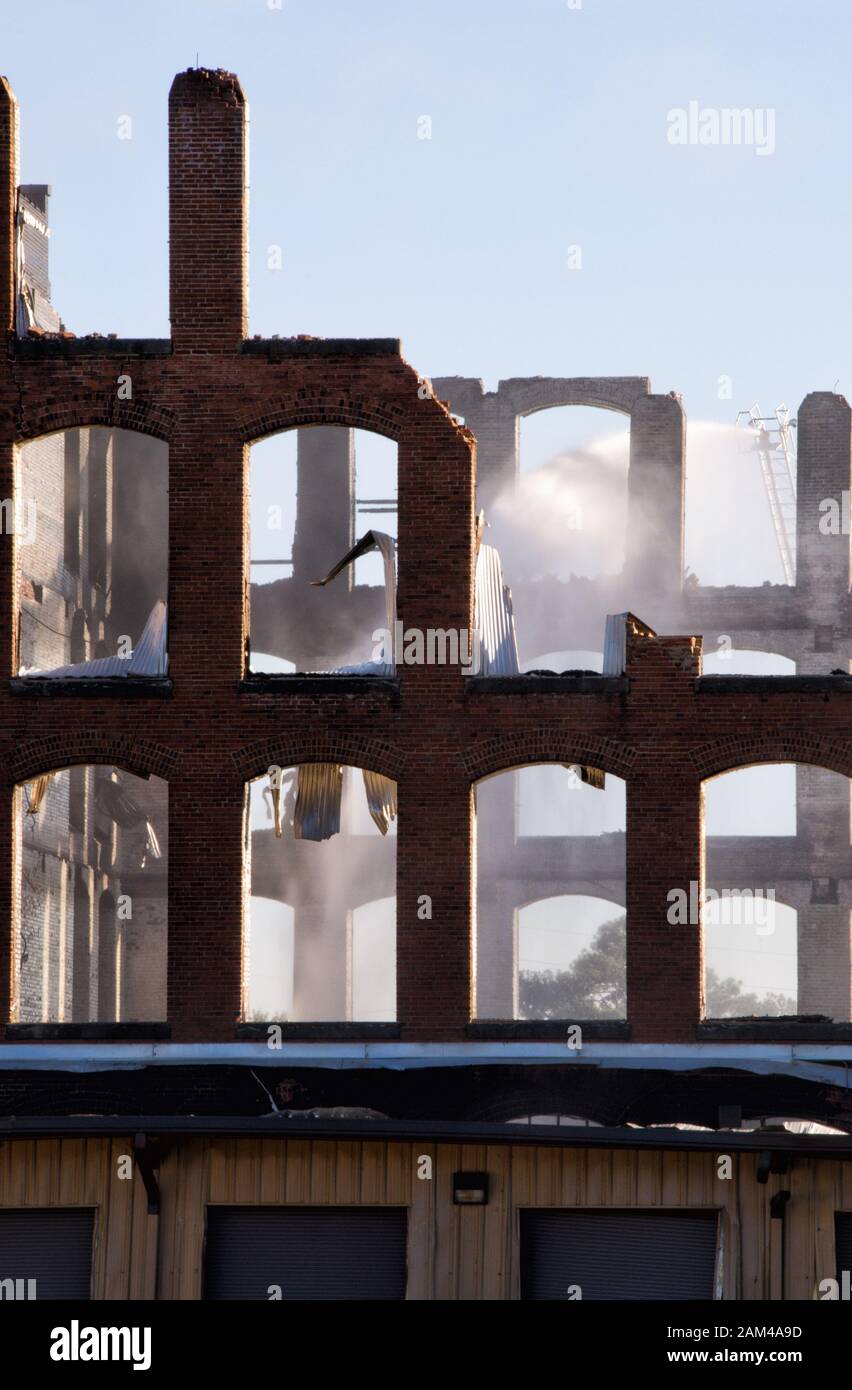 The fire department is extinguishing fires in a burnt out brick building which was an historic textile mill in Bibb City near Columbus Georgia. Stock Photo