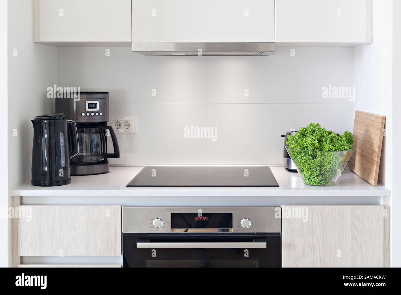 The interior of the kitchen with electric appliances, hood, kettler, coffee maker, stovetop and oven Stock Photo