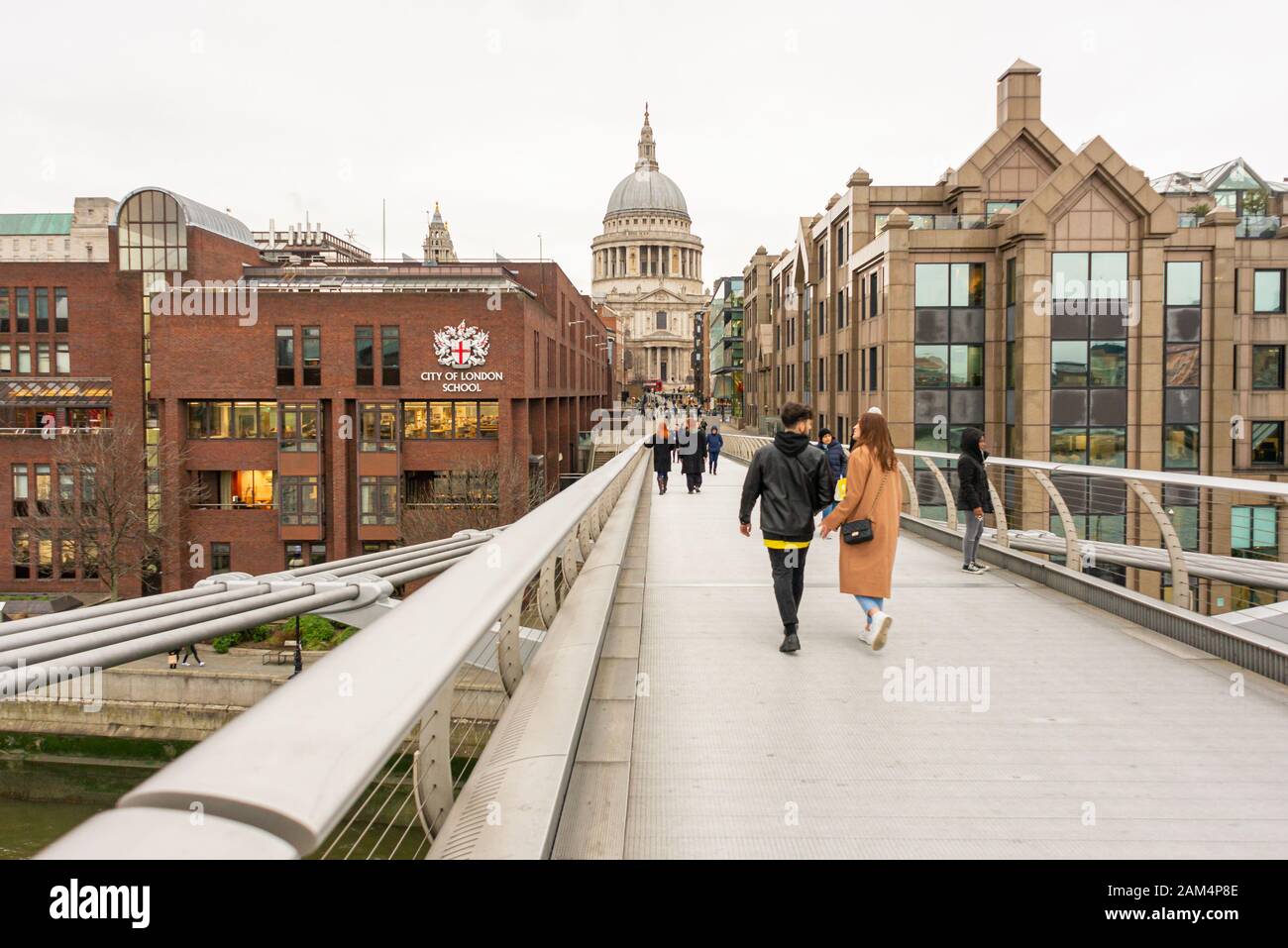 People on Millennium Bridge near City of London School and St Paul's Cathedral, London in winter Stock Photo