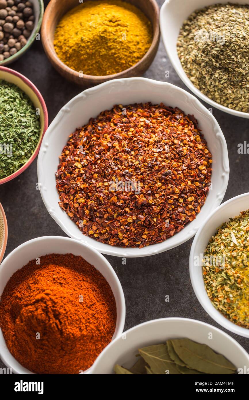 Ground chilli pepper and variety spices and herbs in bowls Stock Photo
