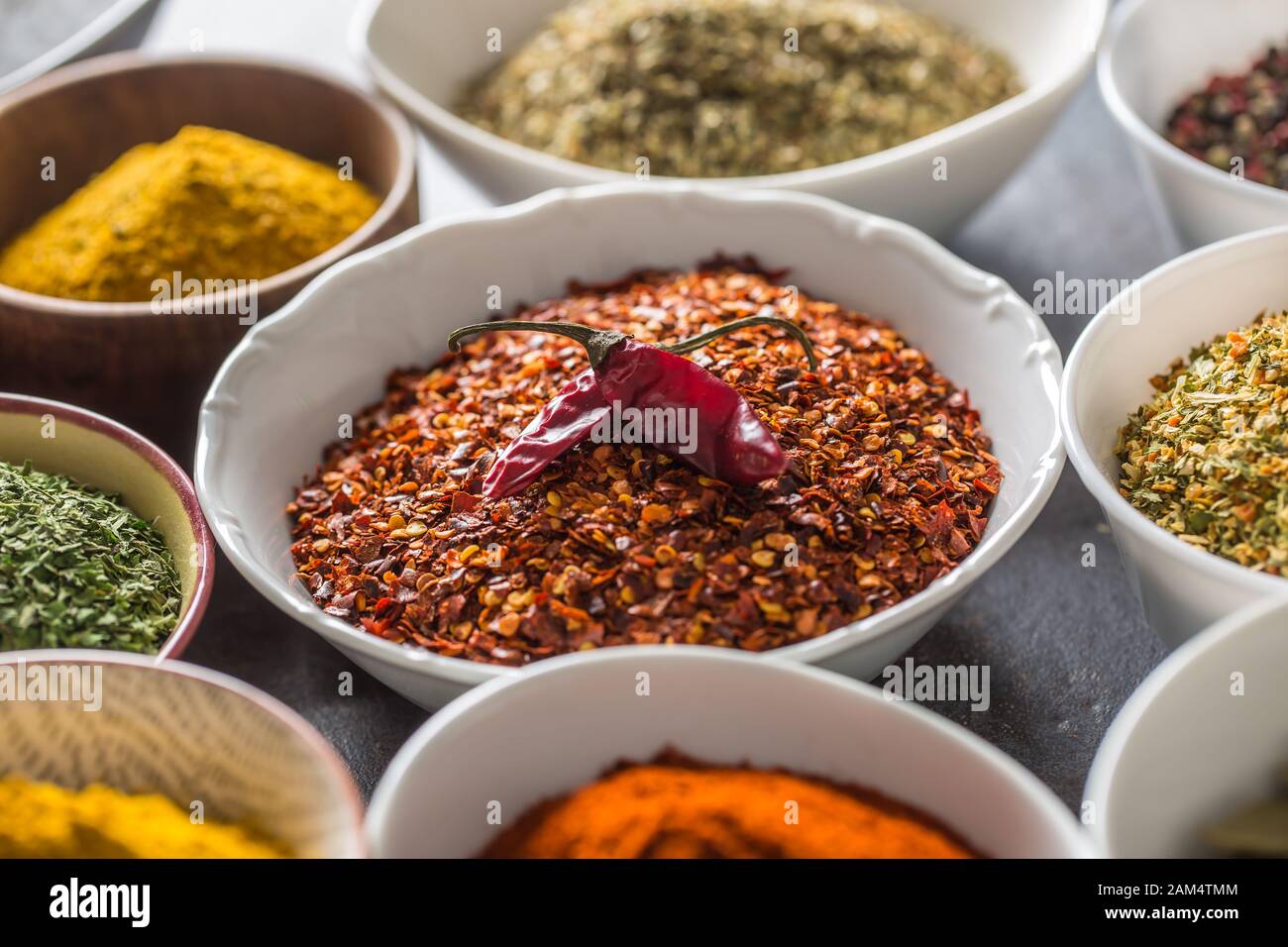 Ground chilli pepper and variety spices and herbs in bowls Stock Photo