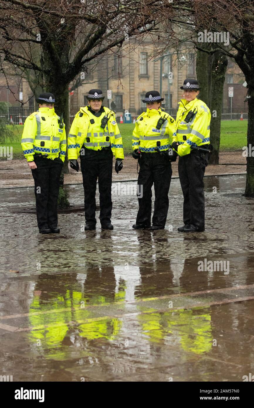 Glasgow, Scotland, UK. 11th Jan, 2020. One of several groups of police officers standing in the pouring rain at the entrance to Glasgow Green as thousands of independence supporters march through the streets of Glasgow. The event has been organised by All Under One Banner, the grassroots pressure group for Scottish Independence Credit: Kay Roxby/Alamy Live News Stock Photo
