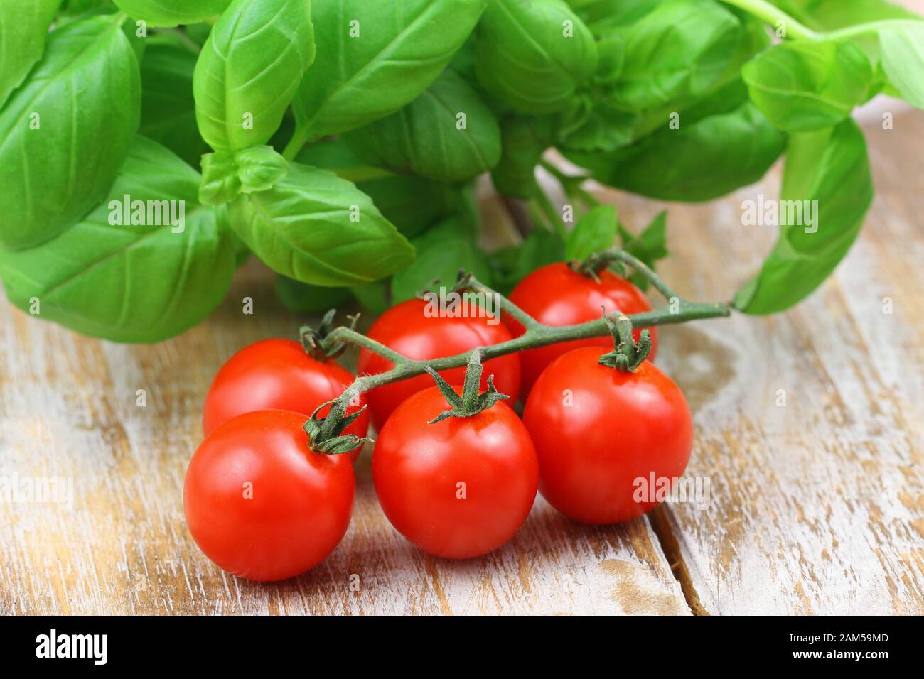 Delicious cherry tomatoes and fresh lettuce on wooden surface Stock Photo