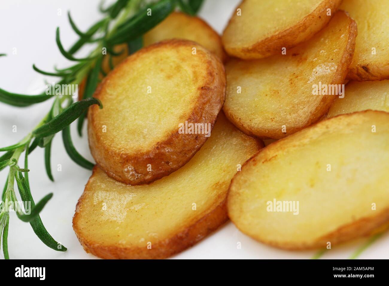 Crunchy fried potato slices with peel with fresh rosemary, closeup Stock Photo