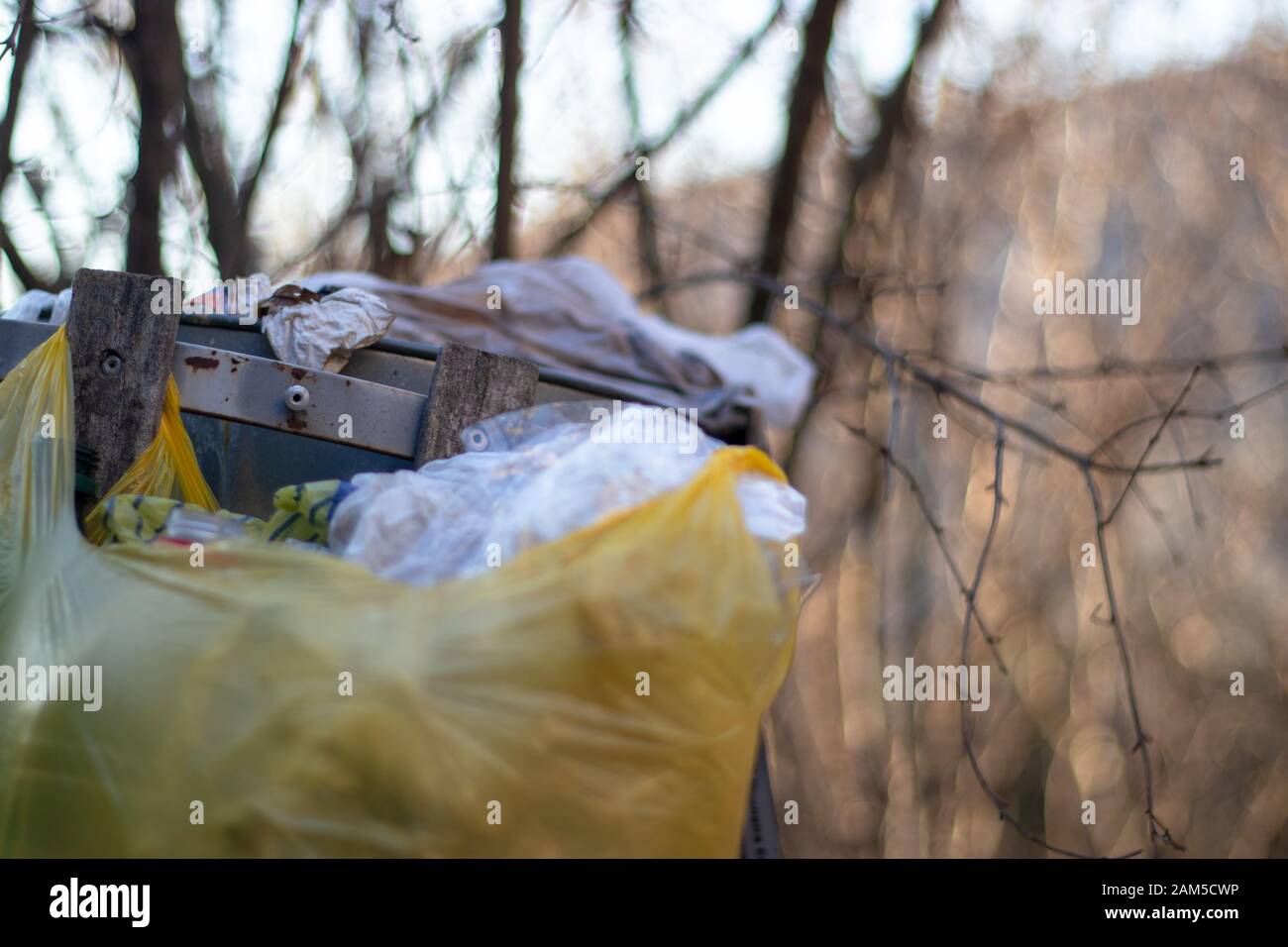 Overflowing trash bin with multiple trash bags around it. Problem with