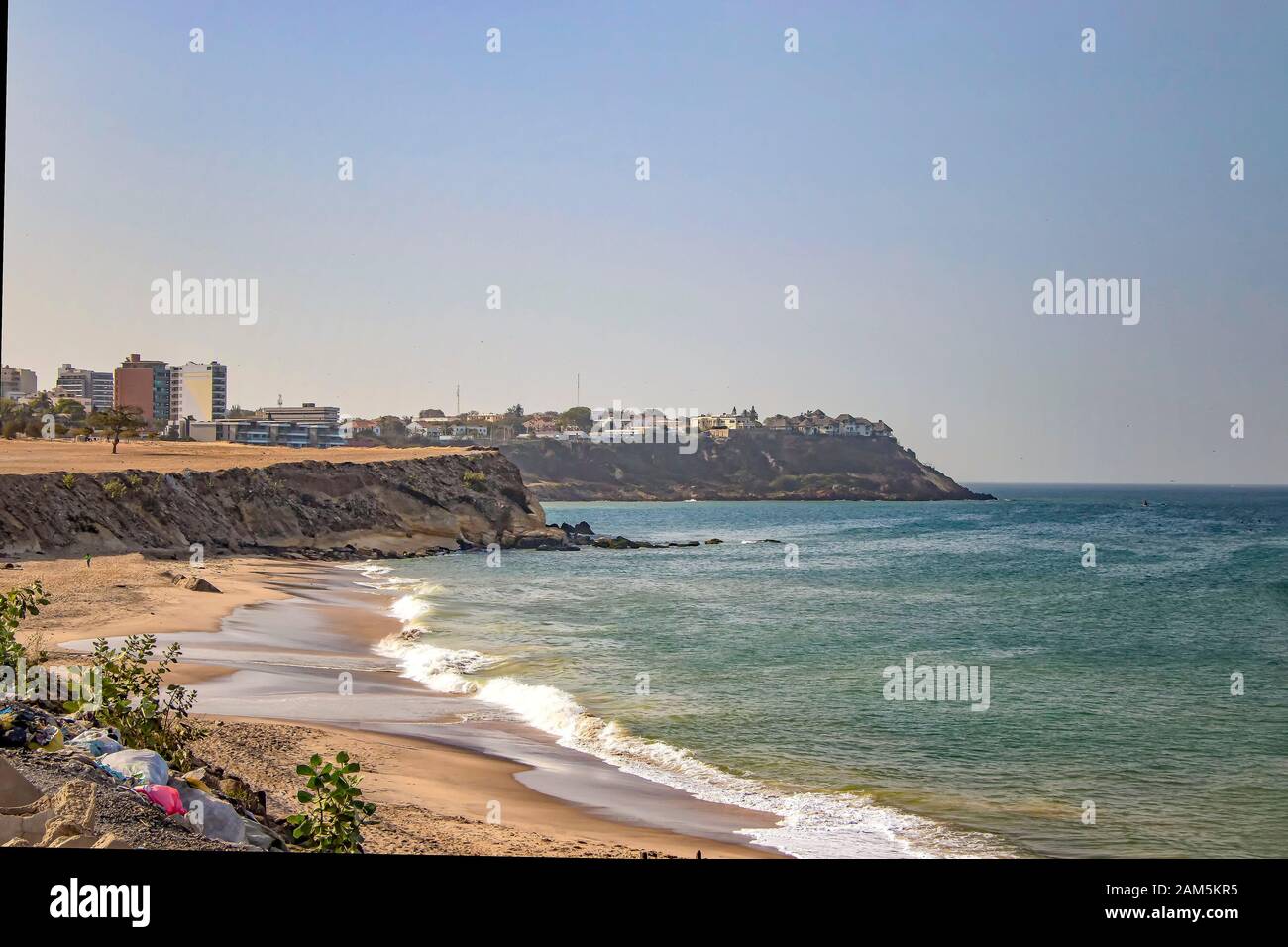 Views of the coastline of Dakar, Senegal, Africa. It is a beautiful long beach and in the background you can see buildings and palm trees and a Stock Photo