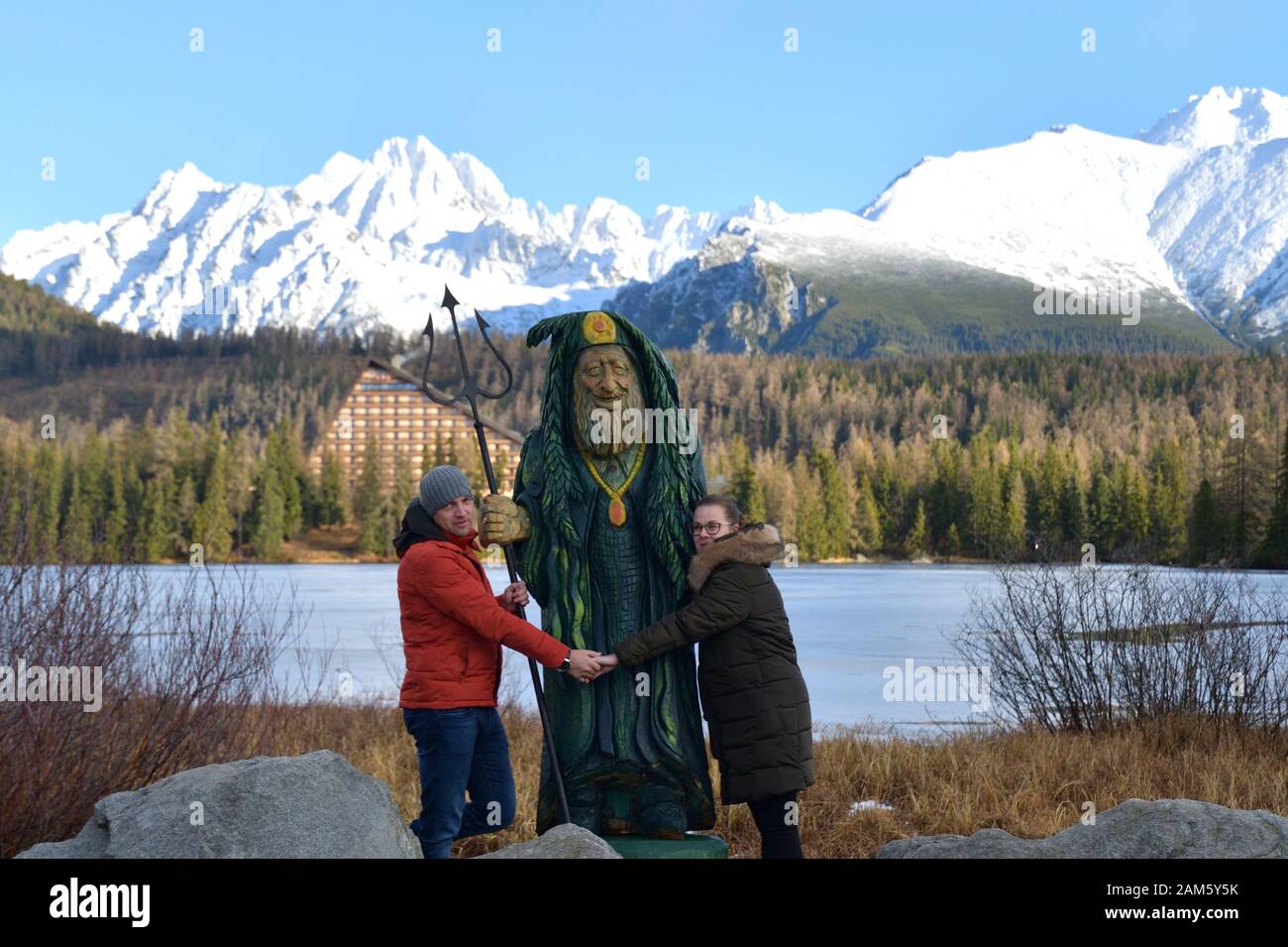 Woman and man fallen in love holding hands in embrace of wooden statue ...