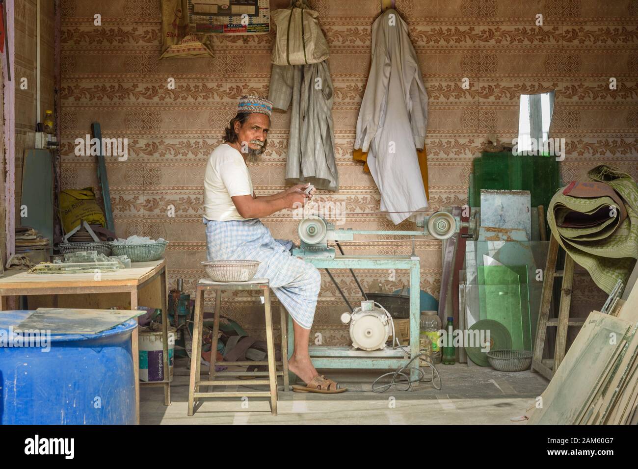 Indian man sharpens pieces of stone on machine in Dharavi Slum at Mumbai. India Stock Photo