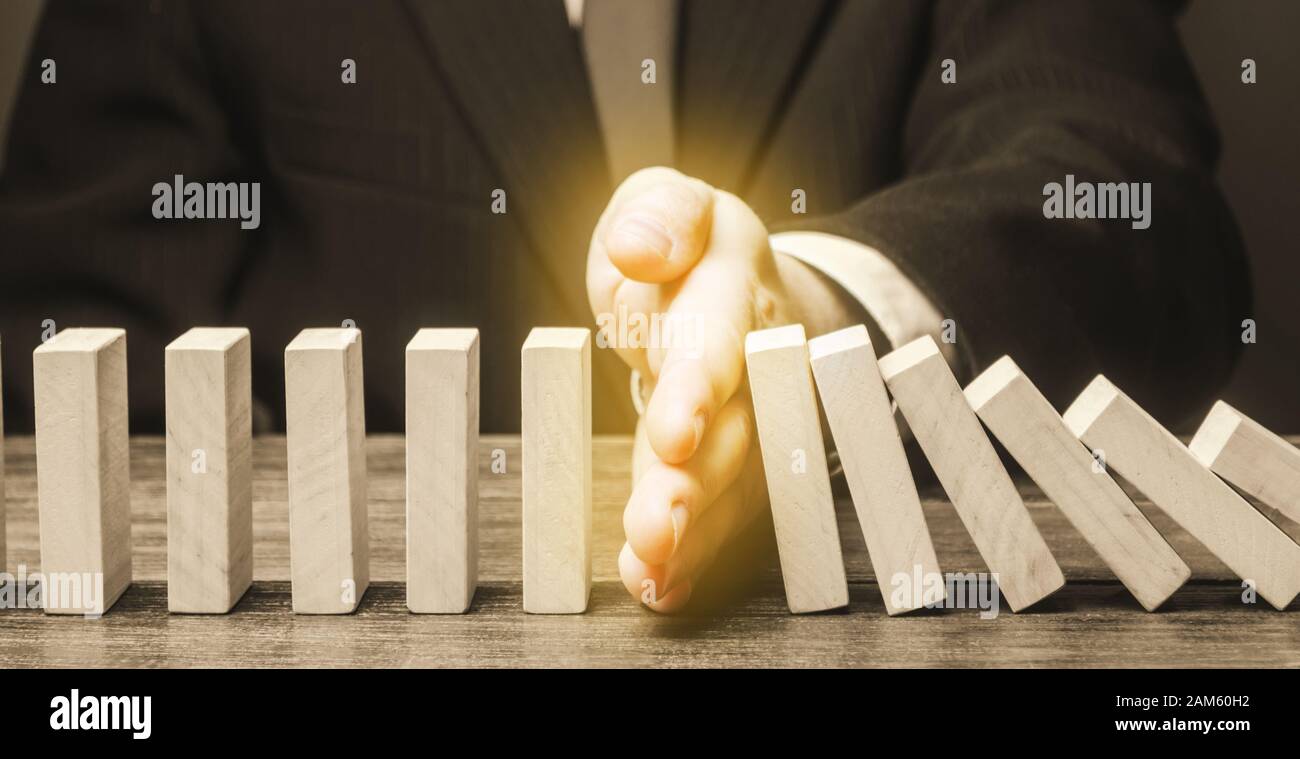 Businessman stops domino falling. Strategy development. Debt restructuring. Risk management concept. Successful strong business and problem solving. R Stock Photo