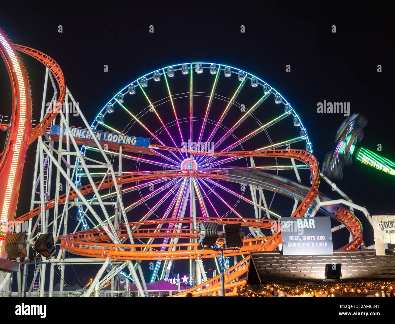 London, England, UK - December 28, 2019: Front view of Ferris wheel and rollercoaster at night in winter wonderland in Christmas holiday Stock Photo