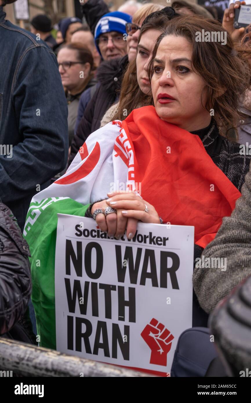 London, UK. 11th January 2020. A woman in the crowd draped in an Iranian flag. Stop the War and CND rally in Trafalgar Square following President Trump's act of war in ordering the assassination of Iranian general Qassem Soleimani in Baghdad, contravening international law and increasing the risk of a major war in the Middle East. Speakers included Lindsey German, Steve Hedley, RMT, Jeremy Corbyn, Diane Abbott, Bruce Kent, Tariq Ali, Sami Ramadani and Andrew Murray. Peter Marshall/Alamy Live News Stock Photo