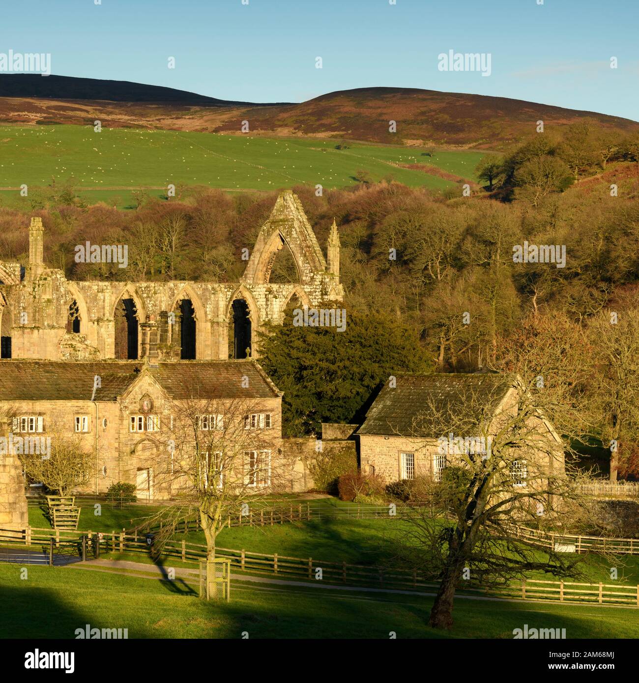 Scenic rural view of ancient, picturesque monastic priory ruins, historic  Old Rectory & sunlit fells - Bolton Abbey, Yorkshire Dales, England, UK. Stock Photo
