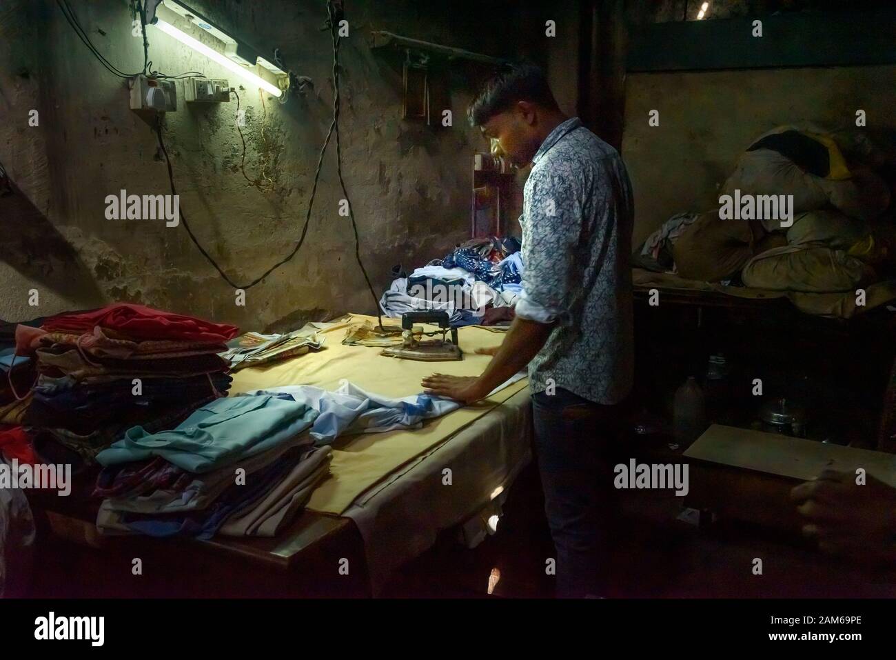 Indian woker ironing clothes in Dhobi Ghat is outdoor laundry in Mumbai. India Stock Photo