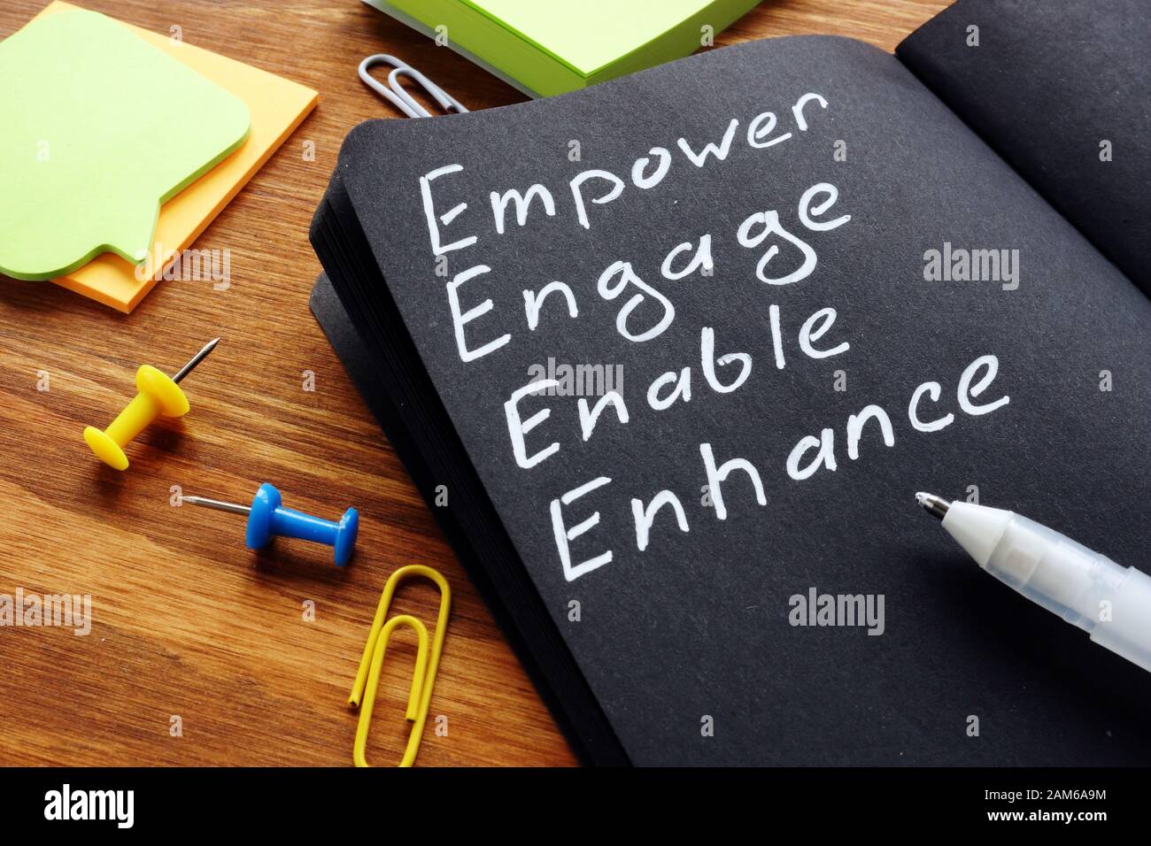 Empower engage enable enhance words written in the notepad. Stock Photo