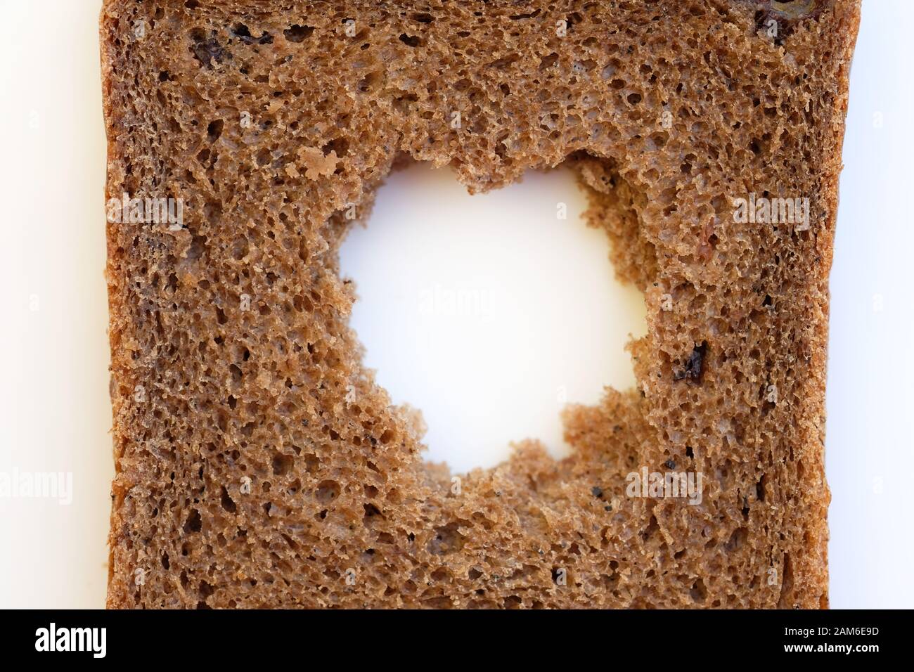 A slice of black bread with a hole in the middle. Rye flour bread on a