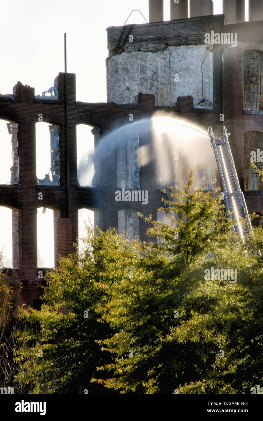 The fire department is extinguishing fires in a burnt out brick building which was an historic textile mill in Columbus GA. Stock Photo