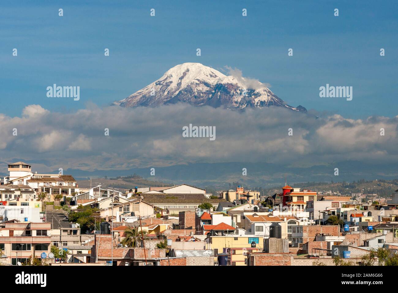 Mount Chimborazo volcano (6268m) seen across the rooftops of the town of Riobamba. Stock Photo